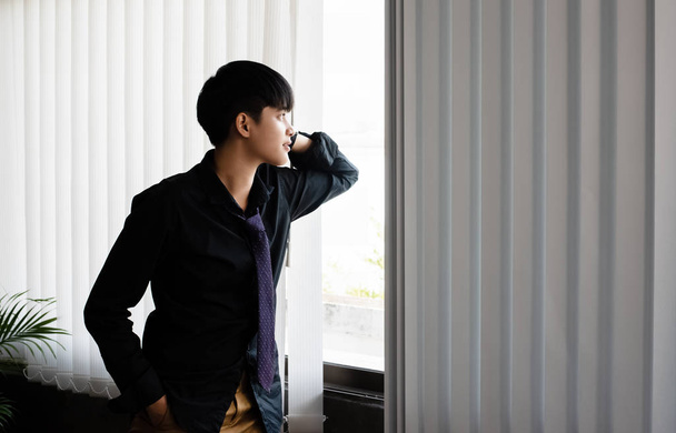 Деловой работник смотрит в окно, отдыхает между работой в офисе, отдыхает
 - Фото, изображение