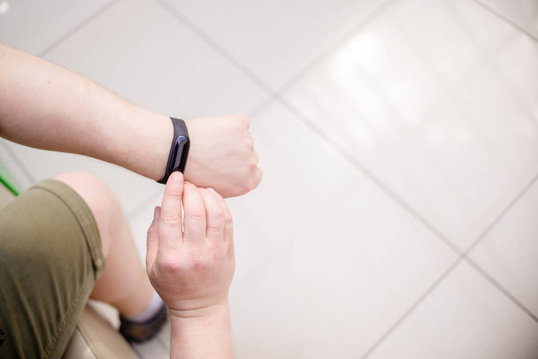 Man draagt een fitness armband. Slimme horloge op de hand van een man. Gepensioneerde met Fitnesstracker. Horizontale top Bekijk van objecten - Foto, afbeelding