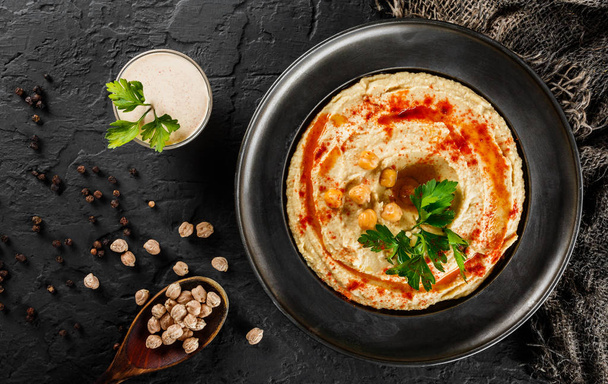 Hummus di ceci con olio d'oliva, paprica in un piatto a m scura
 - Foto, immagini