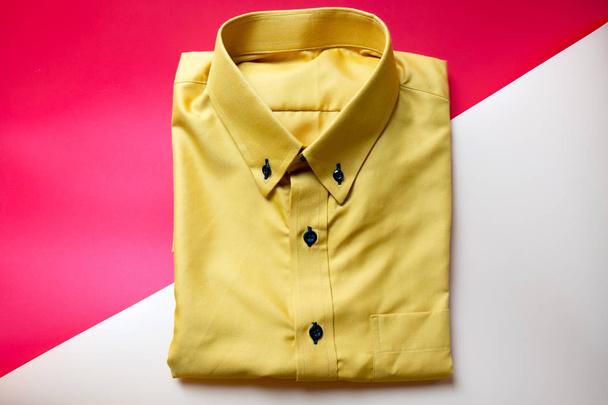 Camisa amarilla sobre fondo rojo y rosa. Concepto de compra y venta
 - Foto, imagen