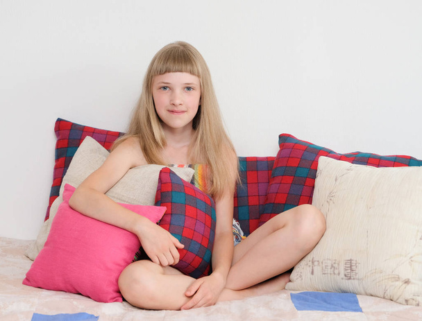Portrait of a cute girl sitting among pillows - Фото, зображення