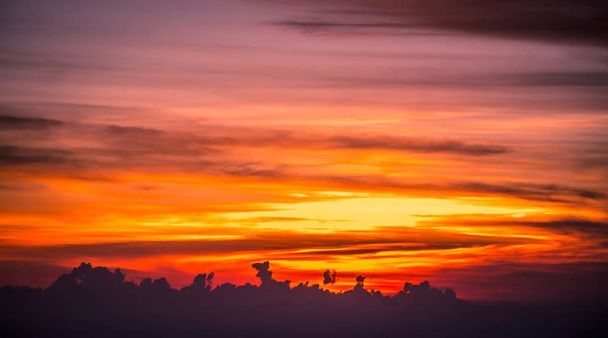 pilvien yli laskeva aurinko näköala lentokoneesta
 - Valokuva, kuva