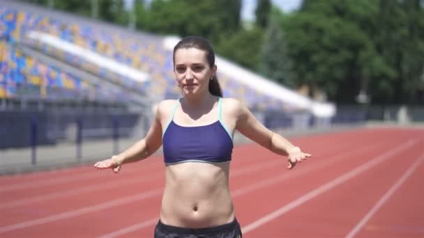 4k. fiatal sportos nő stretching testület előtt fut a stadionban - Felvétel, videó