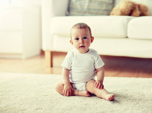 happy baby boy or girl sitting on floor at home - Fotó, kép