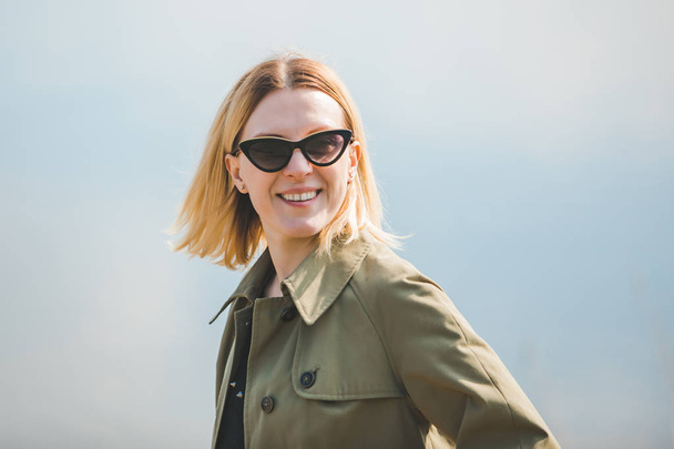 portrait of pretty smiling blond woman in sunglasses and coat - Foto, immagini