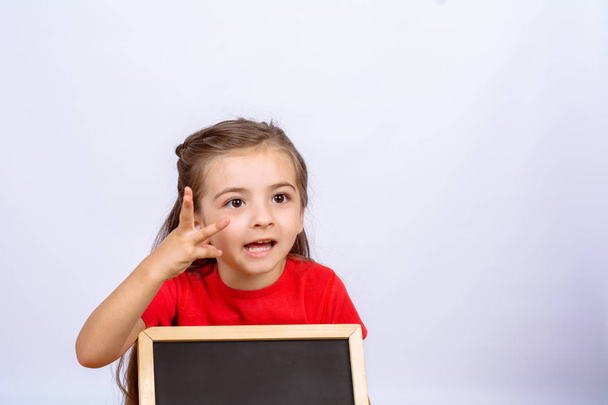 Little girl holding chalkboard. - Foto, afbeelding