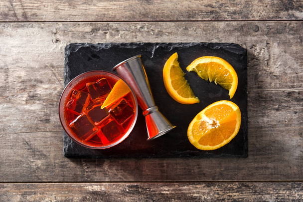 Negroni-Cocktail mit Orangenstück im Glas auf Holztisch. Ansicht von oben - Foto, Bild