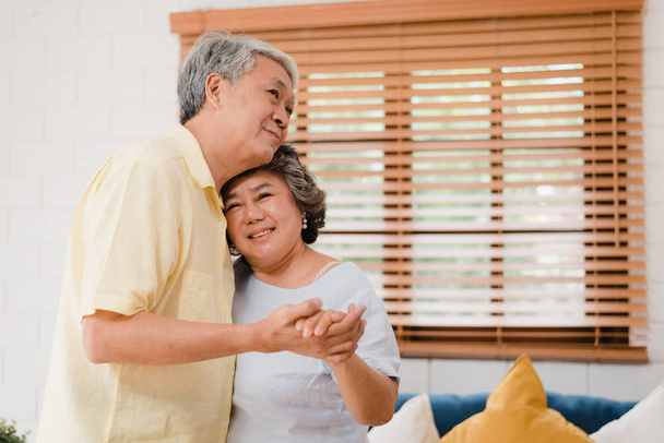 Ázsiai idős pár táncol együtt, miközben zenét hallgatni a nappaliban otthon, édes pár élvezi a szerelem pillanatát, miközben szórakozik, amikor nyugodt otthon. Életmód nyugdíjas család pihenni otthon koncepció. - Fotó, kép