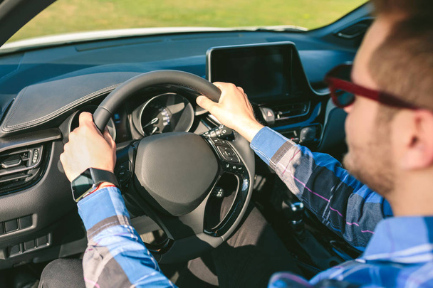 Молодой человек держит руль во время вождения автомобиля
 - Фото, изображение