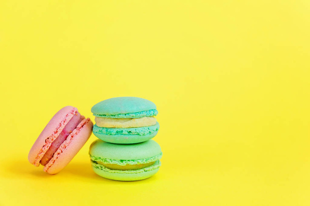 French sweet cookie. Minimal food bakery concept. Blue and pink macaron on yellow background - Фото, изображение