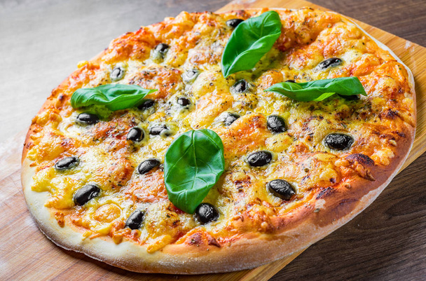 Mozzarella peynirli pizza, domates, biber, zeytin, baharat ve taze fesleğen. İtalyan pizzası. Margherita Pizzası ya da Margarita Ahşap masa arkasında - Fotoğraf, Görsel