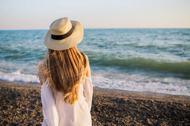 Blonde girl in a hat looking at the sea waves. - Foto, Imagem