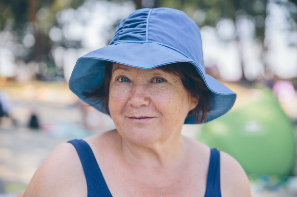 Senior vrouw dragen hoed ontspannen en gelukkig buiten - Foto, afbeelding