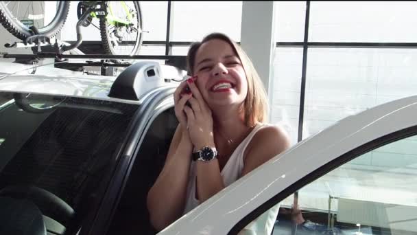 Happy young woman enjoying her first car at car showroom, slow motion  - Imágenes, Vídeo
