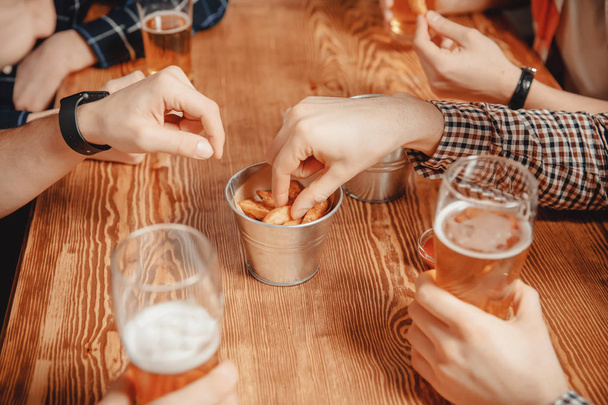 Пиво и крекеры, гренки с соусом. Мужчины в баре за деревянным столом
 - Фото, изображение