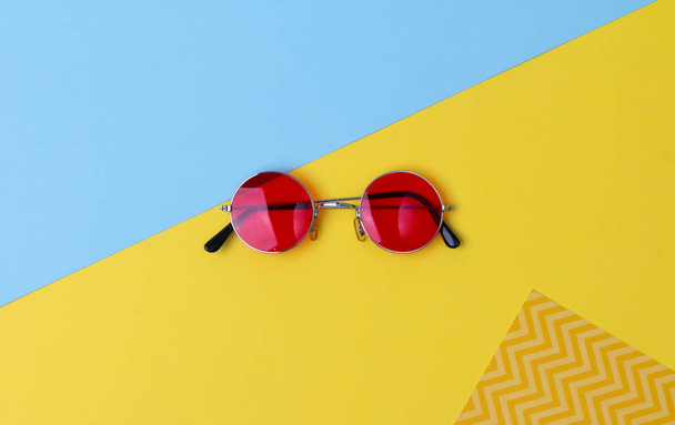 Ronde hipster zonnebrillen met rode lenzen op kleurrijke achtergrond. - Foto, afbeelding