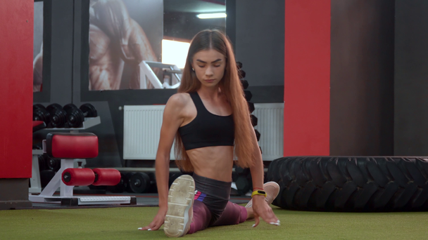 Esercizi statici di stretching per sportivi. Atletica ragazza seduta su spago in palestra
 - Filmati, video