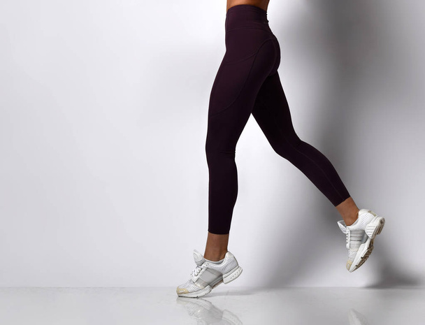 Sporty woman legs walking in sport wear on a white - Фото, зображення