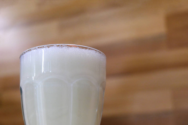Close-up. Beba em um café ou em casa. Vidro com milkshake em um fundo de parede de madeira
. - Foto, Imagem