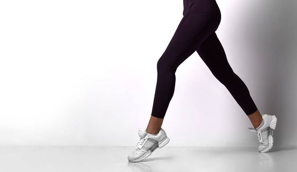 Sporty woman legs walking in sport wear on a white - Фото, зображення