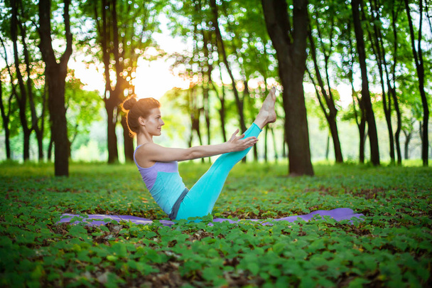 Menina morena fina joga esportes e realiza poses de ioga em uma soma
 - Foto, Imagem