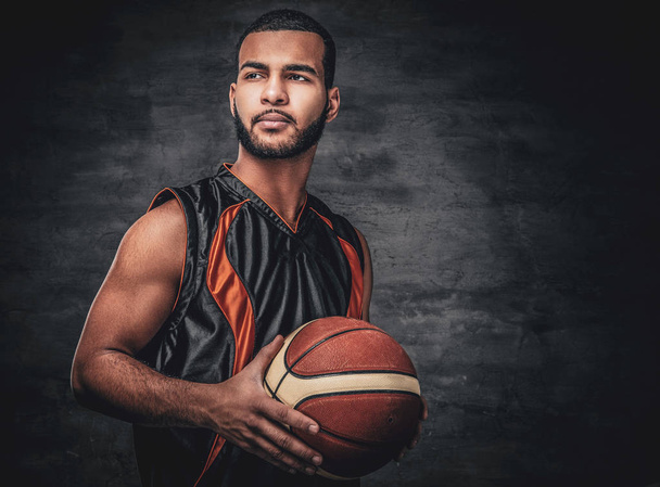 Basketball player holds a ball over grey background. - Photo, Image