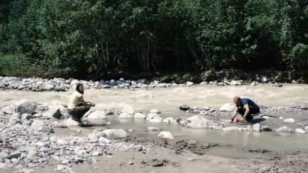 狭い川に座り、スローモーションで生活を楽しむ2人の若い観光客 - 映像、動画