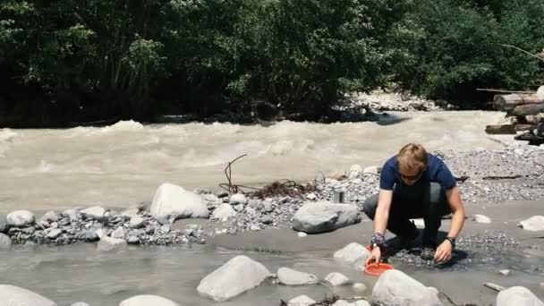 Jeden mladý turista, který sedí a bere vodu z řeky v Georgii v roce - Záběry, video