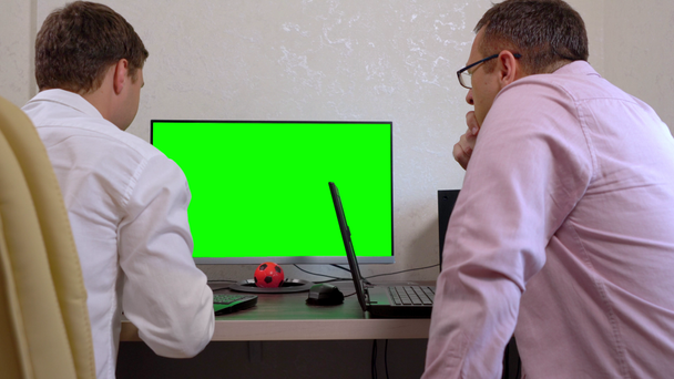 Zwei Männer arbeiten gemeinsam an synchronisierten Computern - Filmmaterial, Video