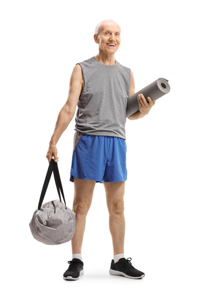 Senior man standing and holding a sports bag and an exercise mat - Foto, immagini