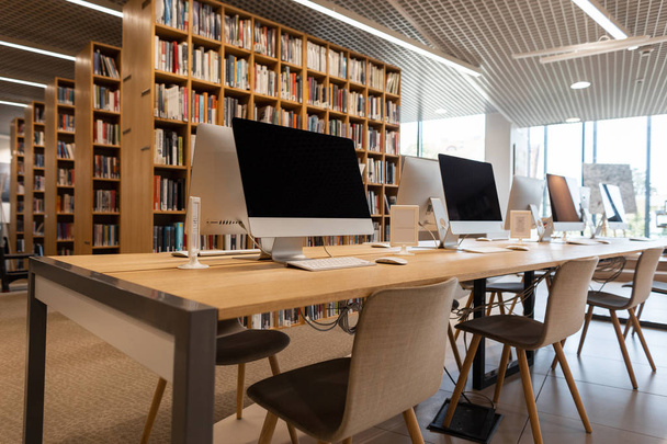 Salle informatique vide dans la bibliothèque de l'école. Les ordinateurs modernes se tiennent sur une table en bois
. - Photo, image