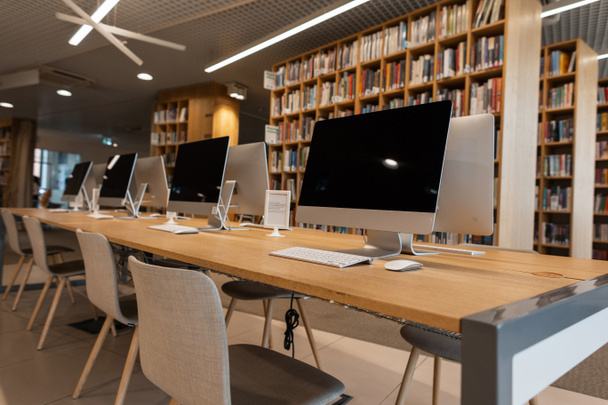 Pokój z nowoczesnymi białymi komputerami w bibliotece uniwersytecki lub college'u. Klasa komputerowa. - Zdjęcie, obraz