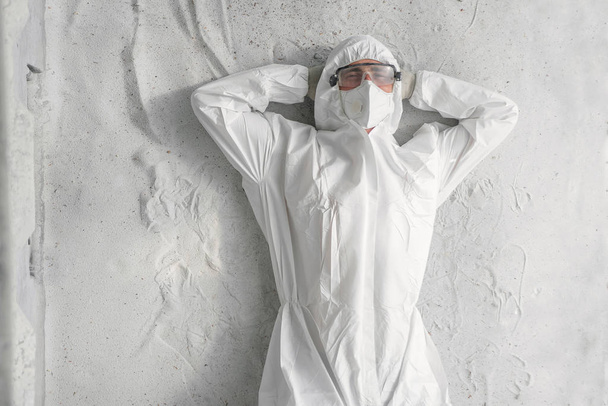 A man in white protective uniform, respirator and plastic transparent glasses. - Фото, изображение