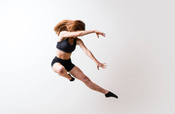 Молода дівчина танцює над ізольованою білою стіною
 - Фото, зображення
