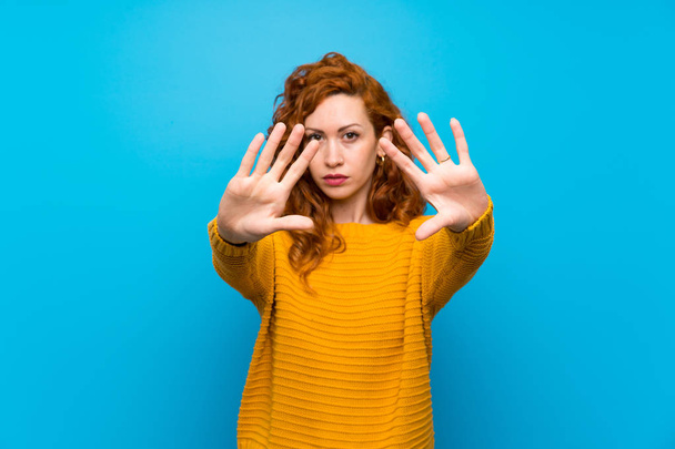 Redhead vrouw met gele trui maken stop gebaar en teleurgesteld - Foto, afbeelding