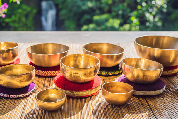 Tibetan singing bowls on a straw mat against a waterfall - Фото, изображение