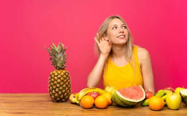 Giovane donna bionda con un sacco di frutta ascoltando qualcosa
 - Foto, immagini