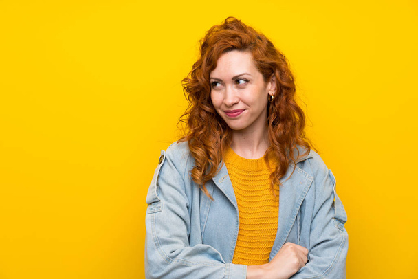Redhead woman over isolated yellow background standing and looking to the side - Фото, зображення