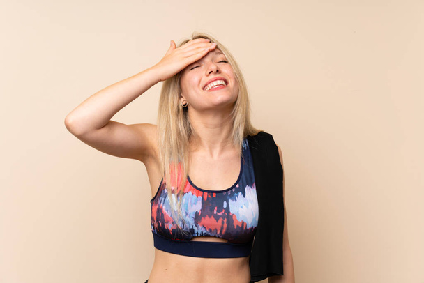 Jonge blonde Sportvrouw over geïsoleerde muur lachen - Foto, afbeelding