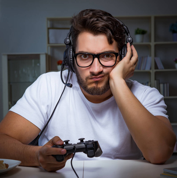 Nuori mies pelaa pelejä pitkiä päiviä myöhään toimistossa - Valokuva, kuva