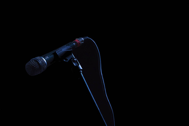 Microfono en su base, en fondo negro con luz que lo delinea - Foto, Bild