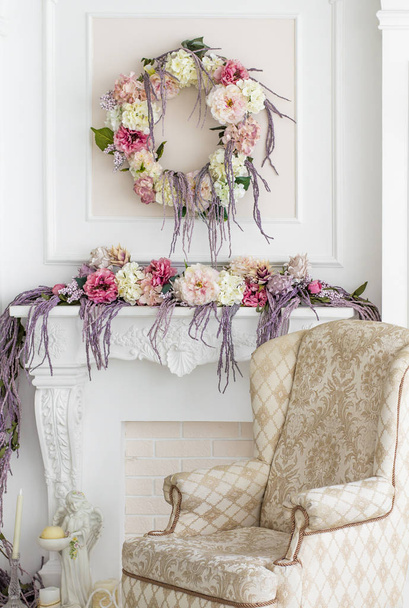 Floral decoration in the photo studio. Interior photo studio. Wedding decorations. Gentle spring flowers. flower composition. Armchair, candle and statuette of an angel - Foto, imagen