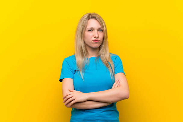 Jeune femme blonde sur fond jaune isolé se sentant bouleversé
 - Photo, image