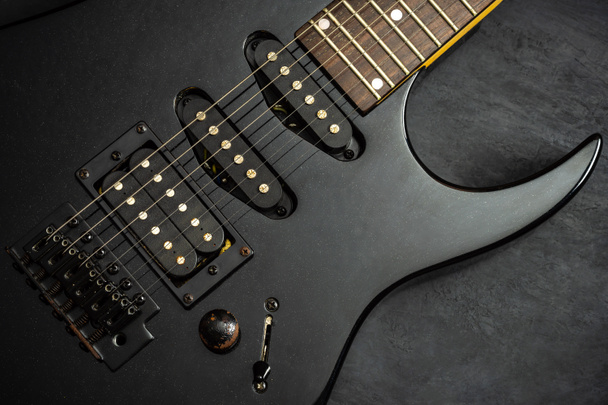 schwarze E-Gitarre auf schwarzem Zementboden. - Foto, Bild