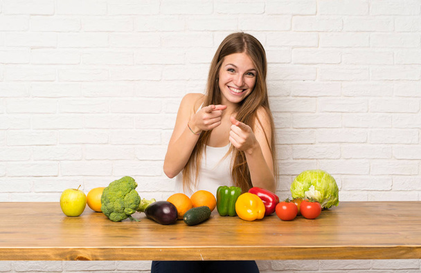 Giovane donna con molte verdure punta il dito contro di te
 - Foto, immagini