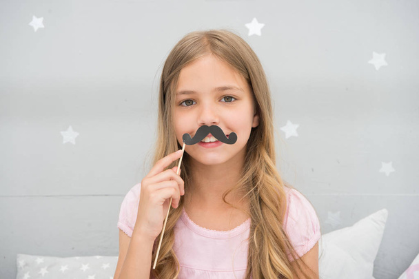 Having fun with fake mustache. Happiness and humor concept. Kid long hair happy smile face. Girl carefree child having fun with mustache. Play with mustache photo booth props. Hair care and beauty - Foto, Imagem