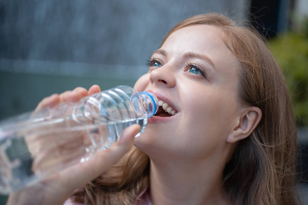 Zbliżenie Portret młodej kaukaski kobieta picie wody z plastikowej butelki - Zdjęcie, obraz