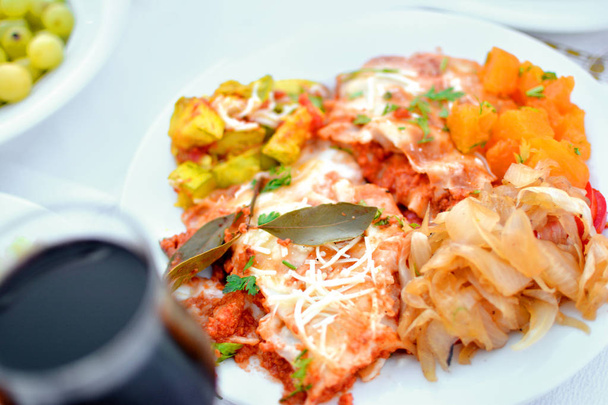 Glass of red wine and food mix vegetables fried and grilled lasagna, onion, pumpkin and zucchini on a plate look appetizing and delicious, tasty, healthy, full of vitamins - Zdjęcie, obraz