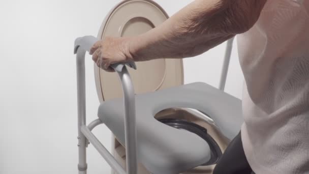 Elderly woman using mobile toilet seat chair - Filmati, video
