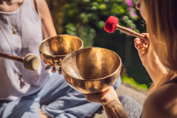 Nepal Buddha copper singing bowl at spa salon. Young beautiful woman doing massage therapy singing bowls in the Spa against a waterfall. Sound therapy, recreation, meditation, healthy lifestyle and - Фото, зображення